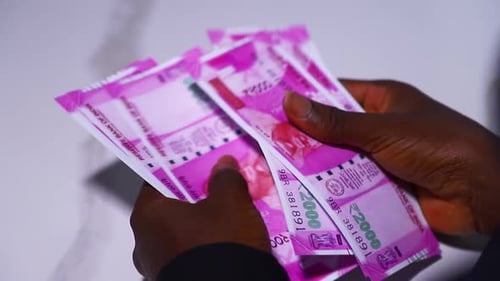 black male in black long sleeves shirt sitting and counting 2000 Indian rupee notes