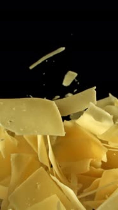 Parmesan Cheese Flakes Fly Upwards on a Black Background Filmed on a Highspeed Camera at 1000 Fps
