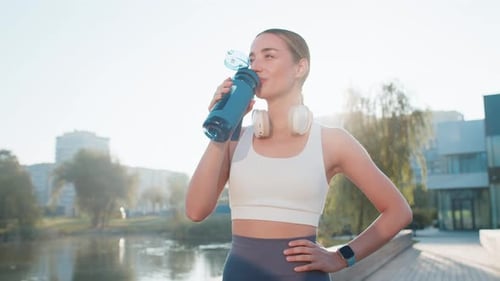 Athletic Fit Sport Runner Girl Woman Drinking Water From Bottle After Training Exercise in Park