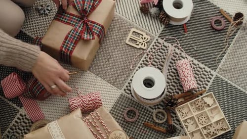 Top view of unrecognizable caucasian woman wrapping Christmas gifts on the floor. Shot with RED heli