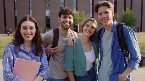 Portrait of group of four caucasian university students sitting outside the university campus. Shot