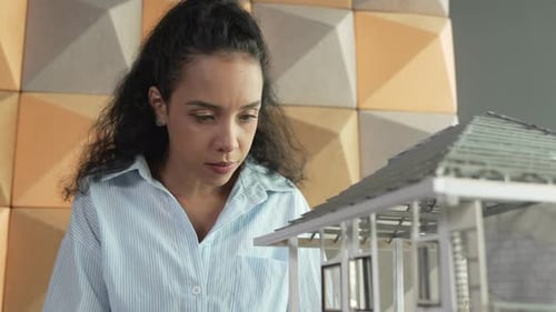 Un ingénieur tient un modèle de maison pendant qu'il inspecte la construction du bâtiment. Manipulateur.