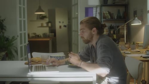 Man Eating Lunch and Using Laptop at Home