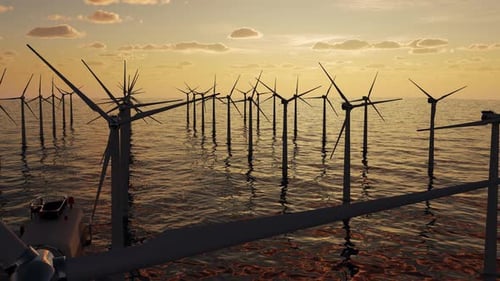 Huge wind turbines generate electricity standing in the sea at sunset.