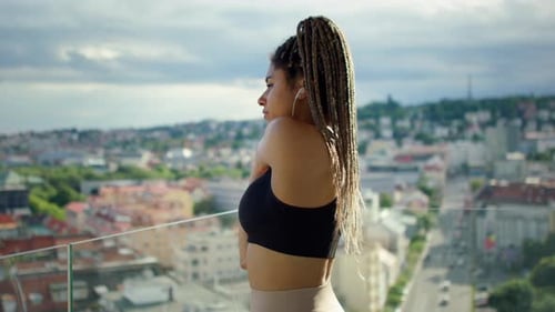 Jeune femme brésilienne s'étirant sur le balcon avec vue sur la ville urbaine