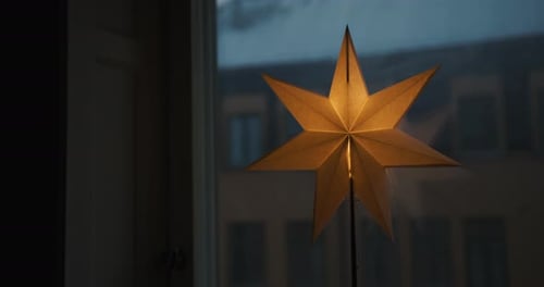 Glowing Holiday Star in Window at Night