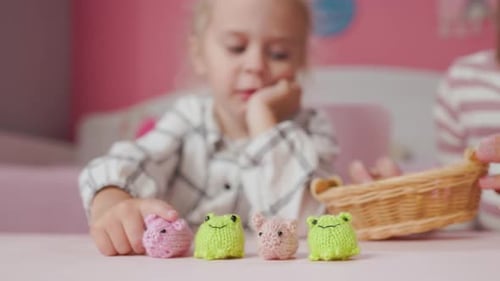 Mädchen spielt mit kleinen gestrickten Tierspielzeugen in einem Zimmer zu Hause