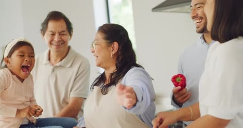 Laughing multi generation family preparing lunch in home kitchen and bonding