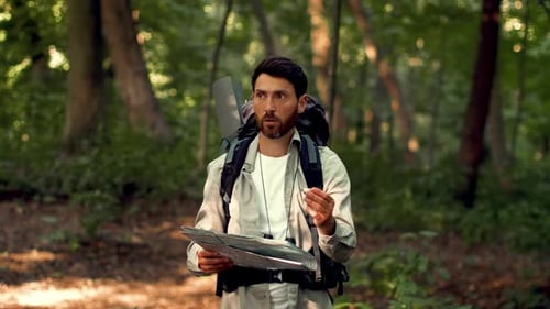 Man With Dark Skin Reading a Map While Hiking in a Forest During Daytime