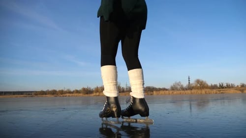 Legs of Woman in Figure Skates Sliding Backwards on Ice Feet of Girl Skating on Frozen River or Lake