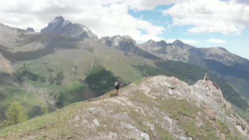 Aerial: Backpacker alpinist hiking to the mountain top, rocky mountain peak dramatic landscape. Summ