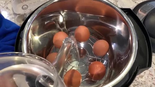 Filling up the bottom of an Instant Pot with water to steam eggs using a stainless steel egg rack. P