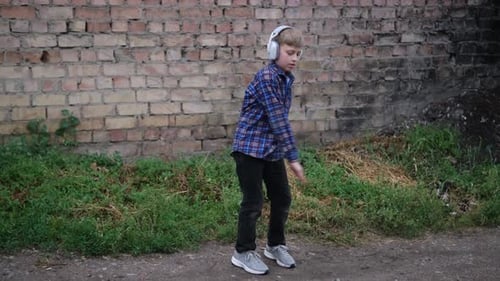 Boy Grooves with Headphones Dancing to Music Outdoors