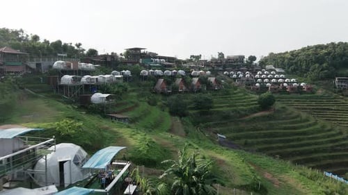 Birds Eye View of a Green Hill with White Houses on Top in Monjam