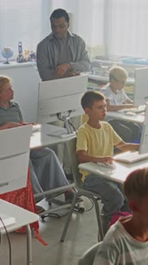 Elementary School Children Using Computers Doing Creative 3D Design Projects Teacher Helping Boys