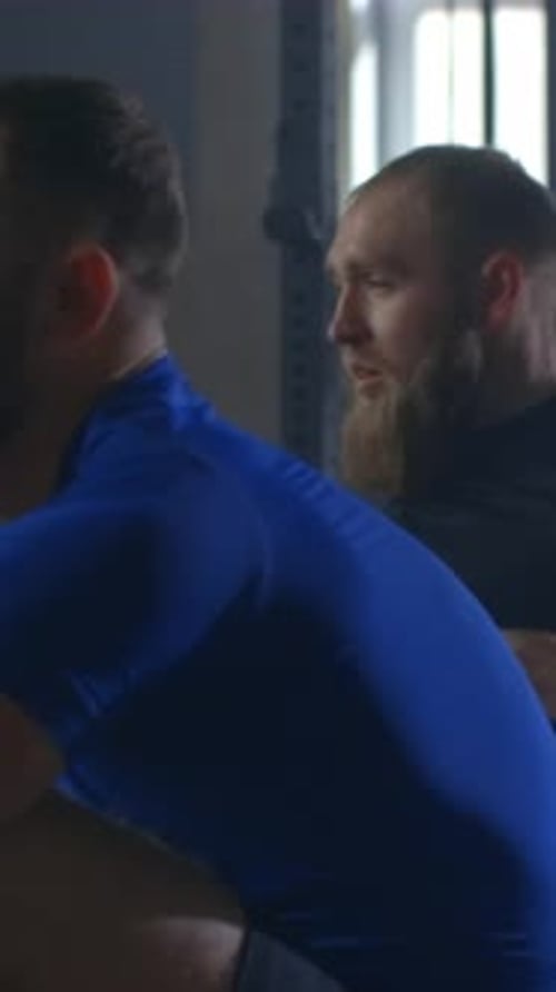 Focused Bearded Athlete Training Intensely on Rowing Machine in Dimly Lit Gym Demonstrating Strength