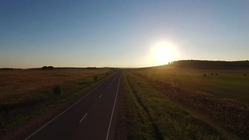 Luftaufnahme über der Asphaltstraße im Feld bei Sonnenuntergang