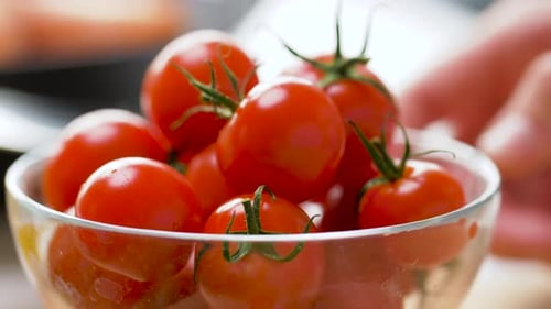 Ripe cherry tomatoes in bowl being spilled onto wood