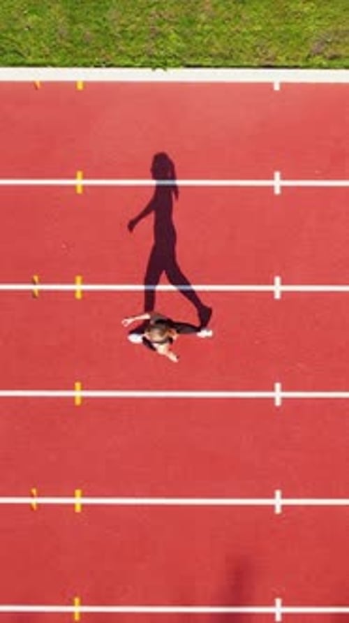 Vertical Aerial View Of Woman Running On Red Athletic Track At Stadium