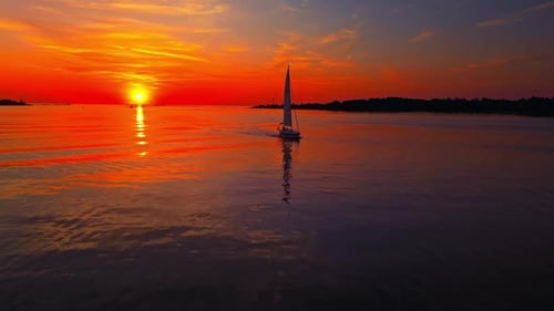 Aerial View of a Sailboat on Tranquil Waters at Sunset Creating a Serene and Vibrant Scenic Beauty
