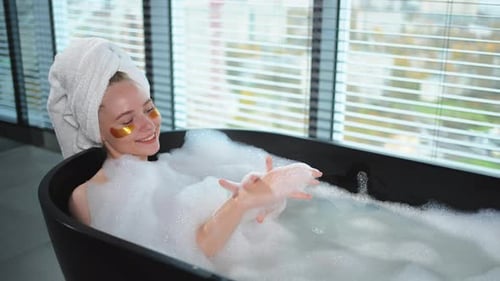 Spa-Entspannung Junge Frau liegt in der Badewanne mit Schaumblasen Mädchen entspannt im Badezimmer zu Hause Hübsch