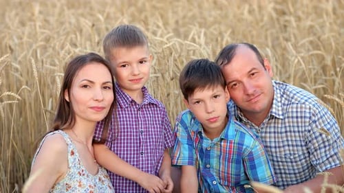 Une famille heureuse montre un sourire plein de dents sur un champ de blé mûr