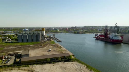 Aerial view of Gdansk harbor, big container ship in foreground, parking lots and Plant site, panning