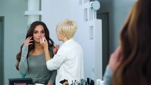 Makeup Artist Applying Cosmetics to Model in Studio