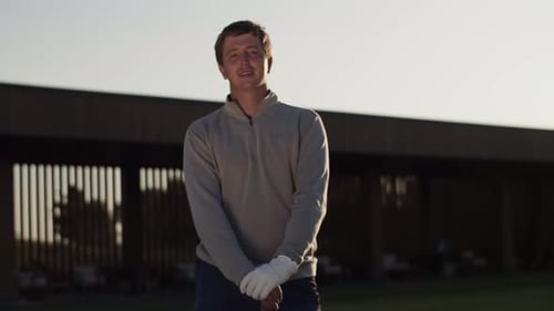 Positive Man in Golf Glove and with Club Stands on Sunset Course