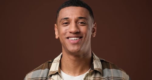 Young African American Man Satisfied Happy Guy Looking at Camera Standing Over Brown Studio