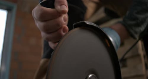 Worker’s hand gripping electric grinder close-up, cutting metal with powerful precision, sparks