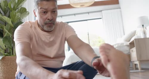 Man Stretching Foot at Home, Mid-Shot