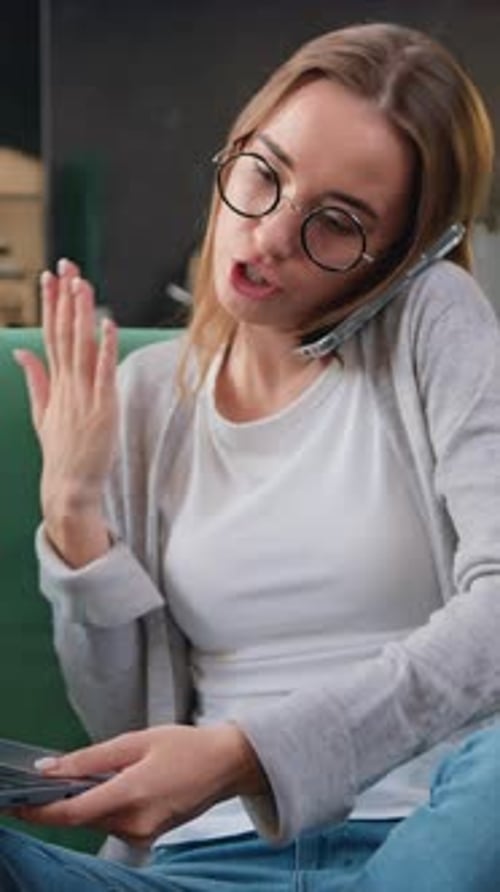 Woman on phone using laptop at home
