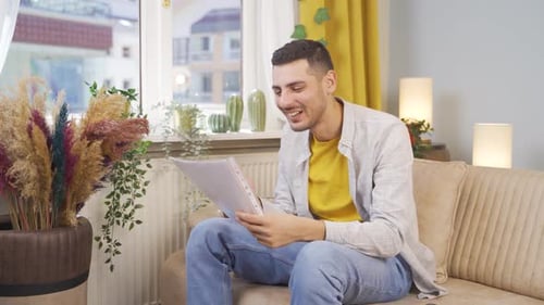 Young Adult Man Reading Documents on Sofa