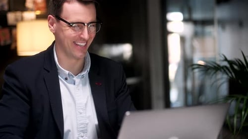 Man Smiling Using Laptop in Office Environment