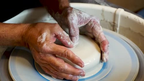 Close up of the potter's hand shaping and molding clay on a turning wheel .