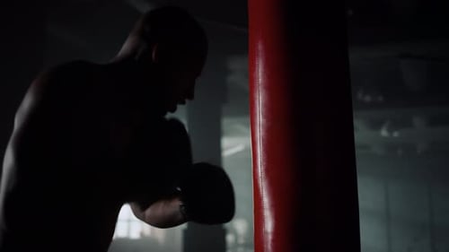 Muscular man boxing with a punching bag at gym