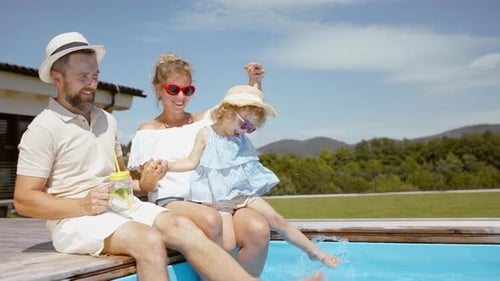 Beautiful Family Sitting on the Edge of the Pool and Having Fun