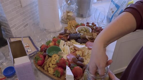 Woman filling a Charcuterie board in a brightly lit kitchen