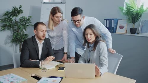 Team Discussing Data on Laptop in Modern Office