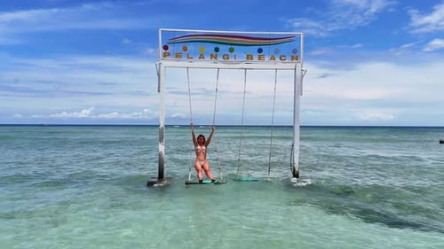 Woman in Bikini on Swing in Ocean