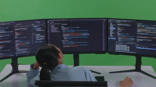 Back View Of Bored Asian Woman Developer Write Code With Multiple Computer Screens In Green Screen