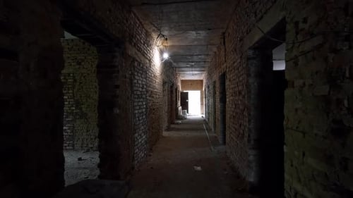 Moving by the long corridor in the old building with brick walls.