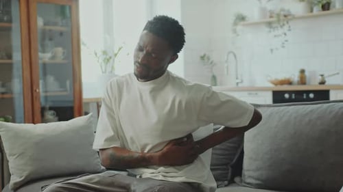 Jeune homme noir souffrant de douleurs abdominales à la maison