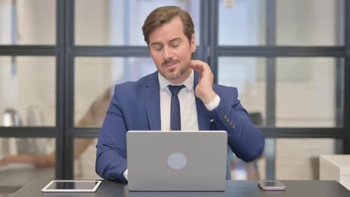 Man Working at Desk Rubs His Neck