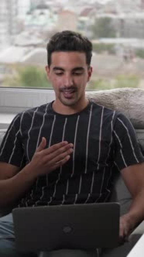 Young Adult Man Video Chatting with Laptop Indoors