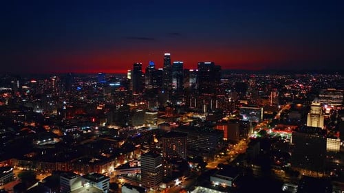 Skyscrapers of night Los Angeles with neon illumination on tops. Red sky above the metropolis