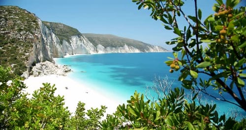 Secluded Fteri beach on Keflaonia Island, Greece. White rocks and blue lagoon surrounded by green fo