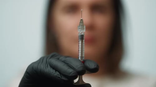 A Woman Doctor Holds a Syringe in Her Hands to Give an Injection