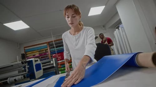 Woman Cutting Blue Material at Workplace Table